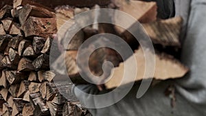 A man takes logs from a woodcutter in his hands for heating in the house. Man is ready for the cold.