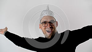 Man takes off his foil hat, bows, smiles, puts a tinfoil helmet to the brains on his head. Emotional handsome guy with glasses.