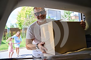 Man takes out box from trunk. View from inside car