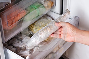 Man takes out frozen fish from the freezer. Frozen fish
