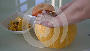 A man takes out the insides of a pumpkin close-up