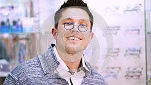 man takes a pair of pince-nez glasses from a small case, tries on them. portrait of Handsome young man choosing