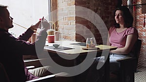 Man takes a photo of his girlfriend. Dating couple relaxing together in chinese tea cafe