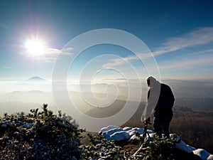 Man takes photos with camera on sharp rock. Dreamy fogy landscape