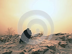 Man takes picture of freeze autumnal daybreak, rocks with powder snow.