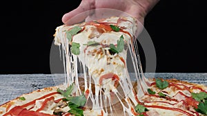 Man takes a piece of pizza with his hand. Frame. Male hand takes the slice of pizza with stretchy cheese