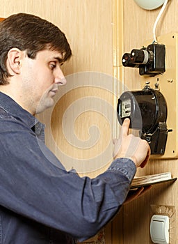 A man records the readings of an electricity meter