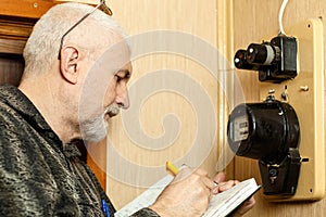 A man records the readings of an electricity meter