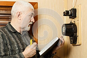 A man records the readings of an electricity meter