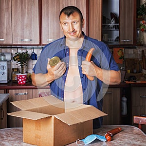 Man takes sausage and canned food from a box. Isolation, animal instincts of self-preservation. Hunger