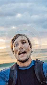 A man takes a selfie on the background of the sea and sunset VERTICAL FORMAT for Instagram mobile story or stories size