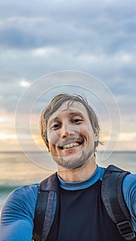 A man takes a selfie on the background of the sea and sunset VERTICAL FORMAT for Instagram mobile story or stories size