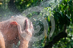 Man takes a shower in the summer garden