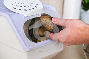 man takes spud from vegetable container. box storing potato, onion, carrot. Container with ventilation, without light