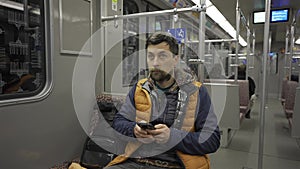 Man takes subway in Berlin, Germany and using smartphone. Male with smart phone on commuter train. Passenger on Berlin