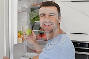 Man taking an apple from the fridge