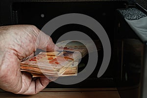 Man taking bundles of cash from inside an open safe