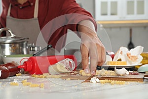 Man taking cheese from table in messy kitchen, closeup. Many dirty dishware, utensils and food leftovers on table