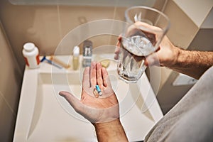 Man taking daily dosage of pills with water photo