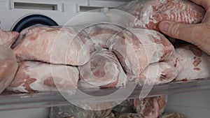 Man Taking Frozen Meat from the Freezer. Frozen Meat Reserves, Portioned in Rations on Freezer Shelves.