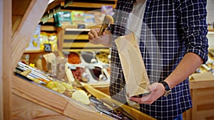 man is taking fruits secs in supermarket, buying by weight in self-service grocery