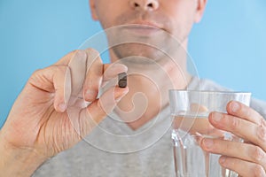 Man taking gastrointestinal adsorbent pill with glass of water for the treatment of intestinal dysbiosis, diarrhea