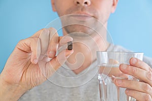 Man taking gastrointestinal adsorbent pill with glass of water for the treatment of intestinal dysbiosis, diarrhea photo