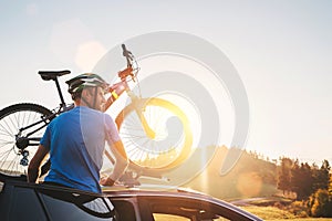 Man taking his bicycle from car roof. Mountain biking concept