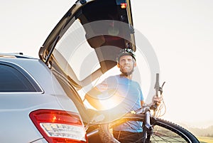 Man taking his bicycle out from the trunk of a car