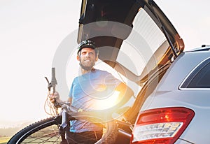Man taking his bicycle out from the trunk of a car