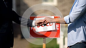 Man taking house keys from estate agent, successful deal, property purchase sale