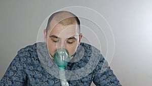 A man taking inhalation. Use a nebulizer and inhaler for treatment. Sick person inhales through inhaler mask. Quarantine