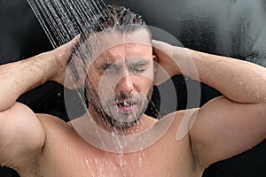 Man taking morning shower. Washing hair under water falling from shower head. Close up guy showering. Body care hygiene