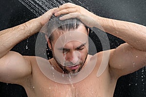 Man taking morning shower. Washing hair under water falling from shower head. Close up guy showering. Body care hygiene