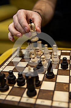 Man taking next step on chess game. Human hand moving wooden white chess king