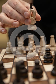 Man taking next step on chess game. Human hand moving wooden white chess king