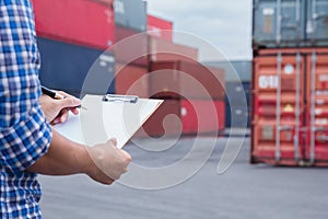 Man taking note checking cargo shipping at container yard area.