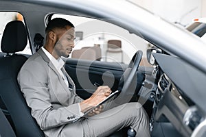 Man Taking Notes Sitting In Driver`s Seat In Automobile Dealership