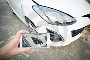 Man taking photo of damaged white car with smartphone