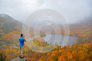 Man taking photo of Echo Lake from Artists Bluff Loop in New Hampshire USA