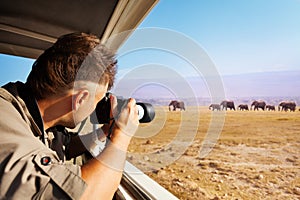 Man taking photo of elephants at African savannah