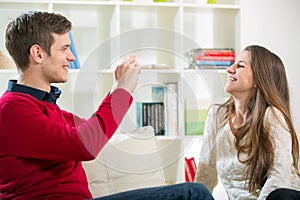 Man taking photo of his pretty girlfriend in the living room