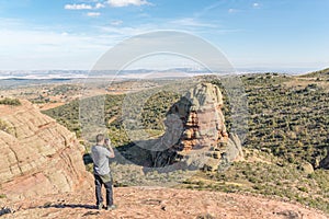 Young man taking a photo of a Rodeno Boulder in Perecens, Teruel, Spain. photo