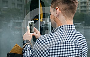 Man taking a photo of a shop window of a fashion store