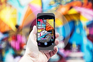 Man taking photo of street art with mobile phone in Shoreditch,