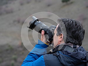 Man taking a photograph with a reflex camera and a zoom lens