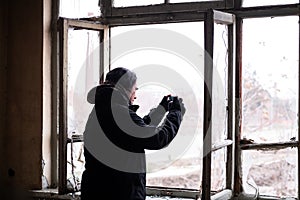 Man taking photos with his mobile inside of an abondened building room on a cold winter day