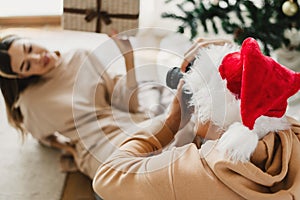 Man taking photos of a woman holding her Christmas gift. Young couple having fun