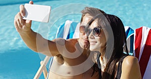 Man taking picture of himself with wife at pool