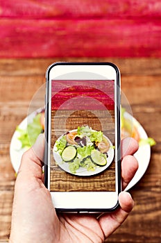 Man taking a picture of a salad with his smartphone